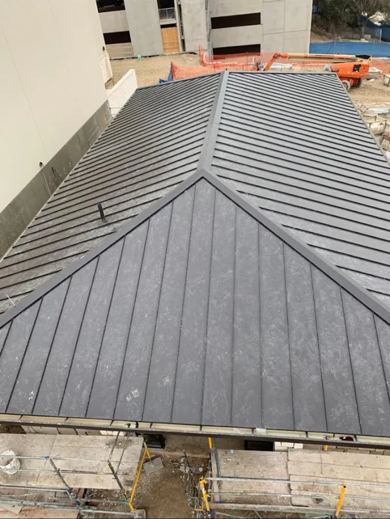 Commercial metal roof construction with crane equipment in Belen